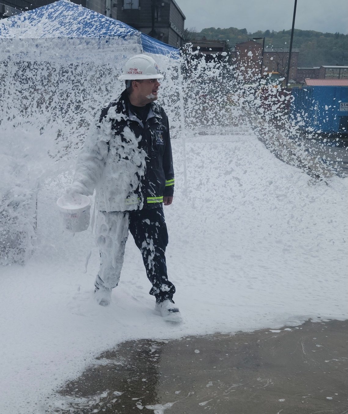 An instructor in Foam Task Force gear walking through a blanket of firefighting foam during a foam drill.